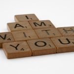 Scrabble tiles spelling 'I Am With You' on a clean white background.